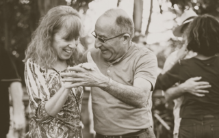An older couple dancing outside a senior living community.