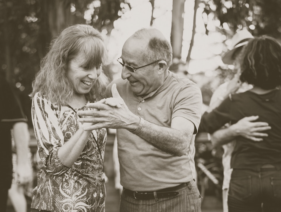 An older couple dancing outside a senior living community.